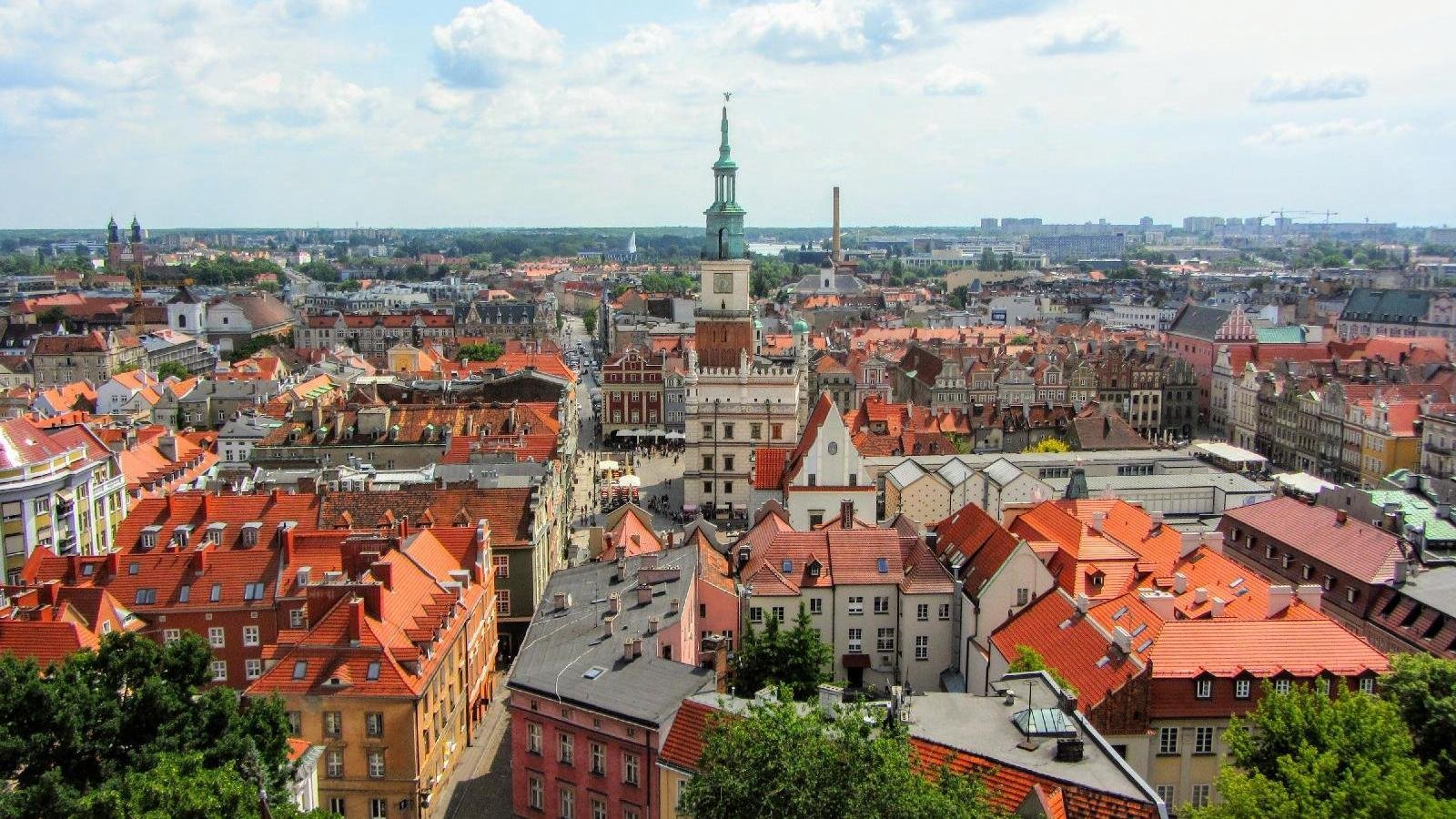 Zdjęcie przedstawia panoramę Poznania z lotu ptaka, w centrum Ratusz i dachy kamienic