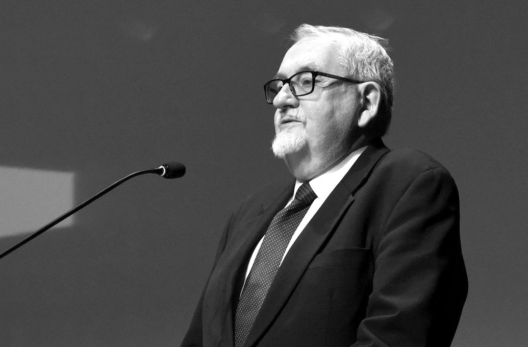 Na czarno-białym zdjęciu profesor stojący przed mikrofonem, podczas jednej z poznańskich debat - grafika artykułu