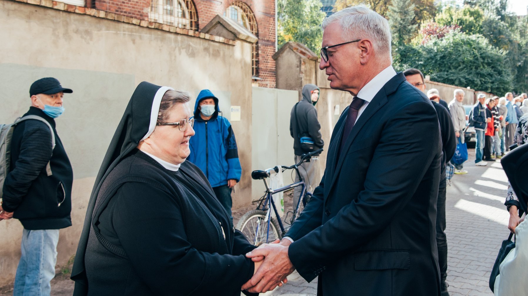 Na zdjęciu Jacek Jaśkowiak, prezydent Poznania, ściskający dłonie siostry Józefy, w tle kolejka ludzi