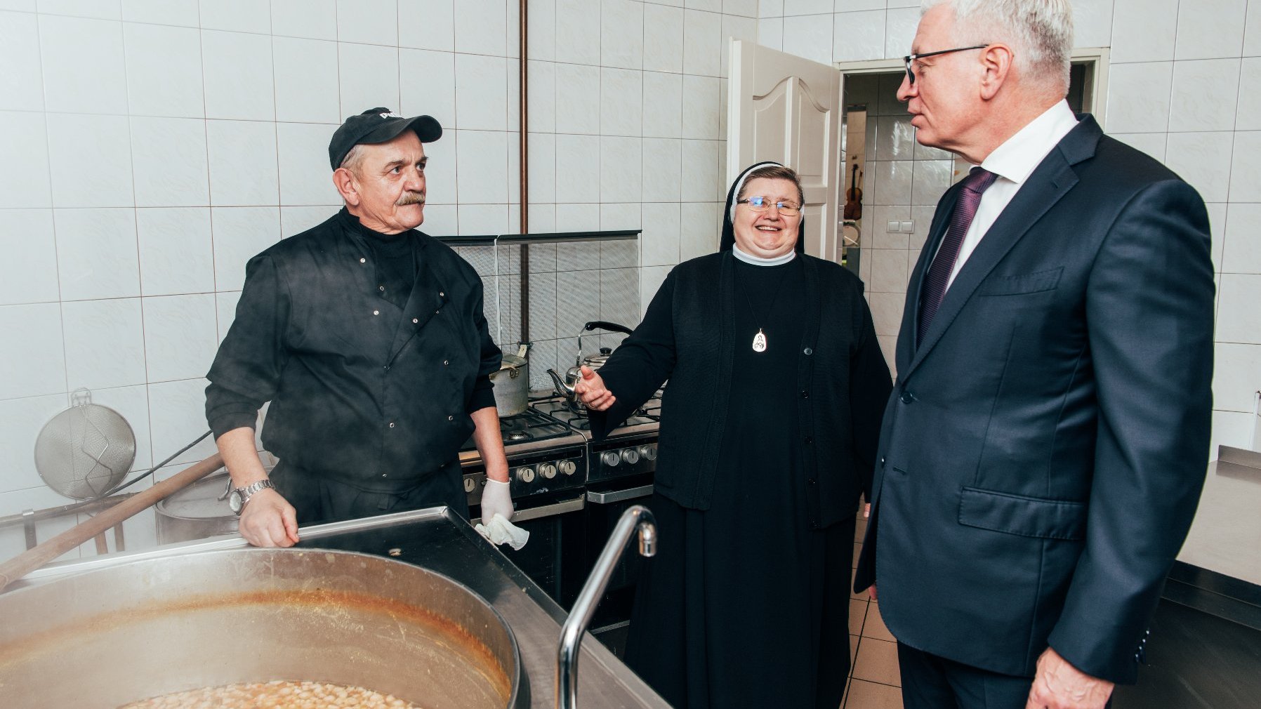 Na zdjęciu Jacek Jaśkowiak, obok siostra Józefa i kucharz, patrzą na ogromny gar pełen grochówki