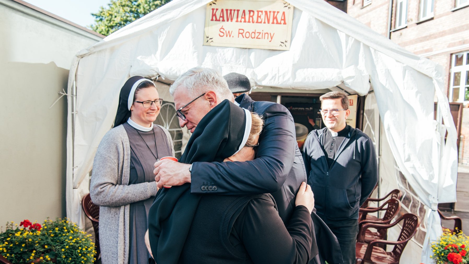 Na zdjęciu Jacek Jaśkowiak, prezydent Poznania, obejmuje siostrę Józefę, w tle namiot z napisem: kawiarenka św. Rodziny