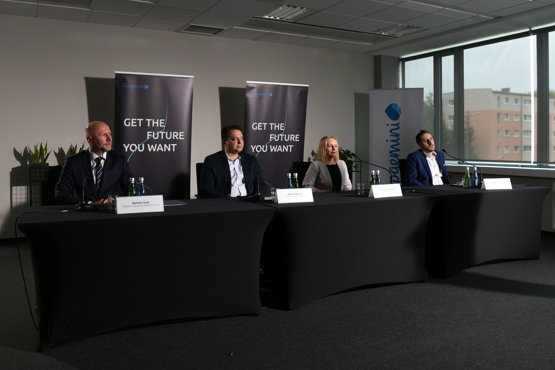 Zdjęcie przedstwia cztery osoby siedzące za stołem konferencyjnym podczas briefingu prasowego. - grafika artykułu