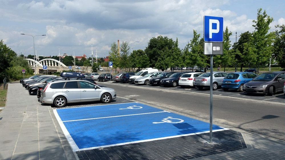 Na zdjęciu parking przed mostem Rocha, na pierwszym planie dwa miejsca dla osób z niepełnosprawnością