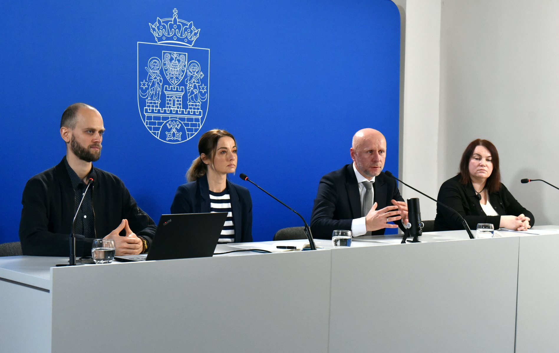 Galeria zdjęć przedstawia zdjęcia z konferencji prasowej. Widać na nich ludzi siedzących za stołem konferencyjnym. - grafika artykułu