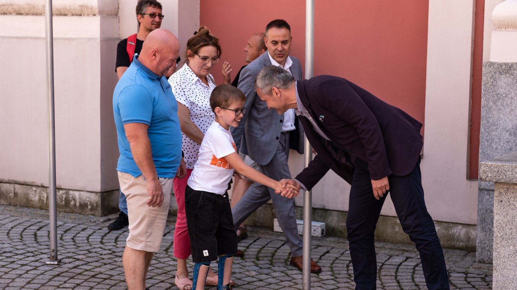 Na zdjęciu zastępca prezydenta Poznania podaje rękę chłopcu, za którym stoją dorośli