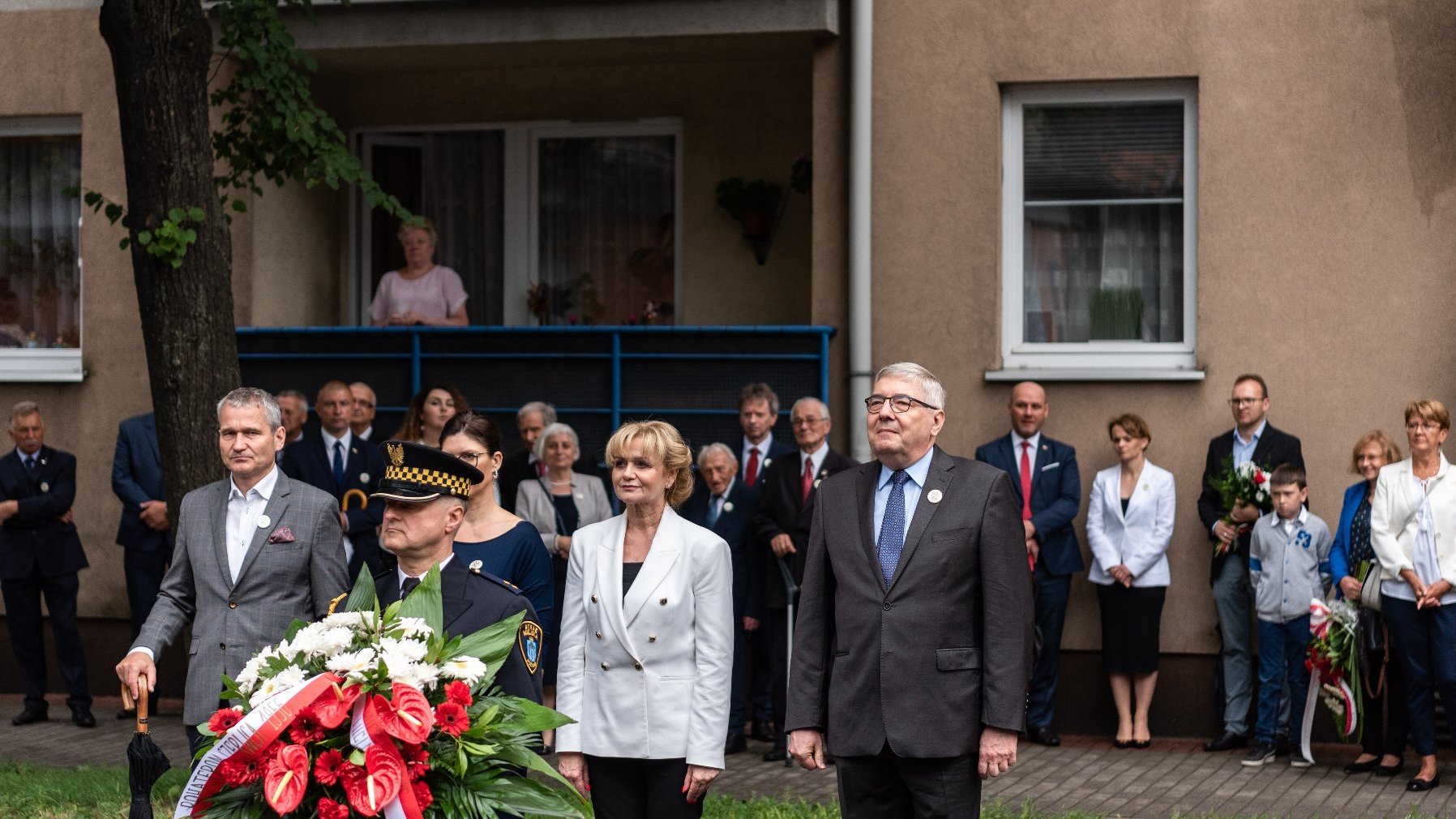 Na zdjęciu dwie kobiety i dwóch mężczyzn składający kwiaty przed tablicą ZNTK, wśród nich przewodniczący rady miasta i zastępca prezydenta Poznania