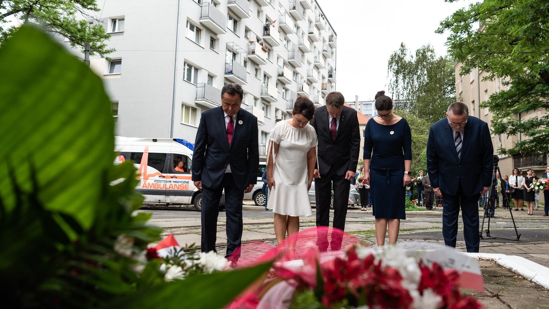 Na zdjęciu pięć osób składających kwiaty przy ul. Gajowej, na pierwszym planie widać wiązanki