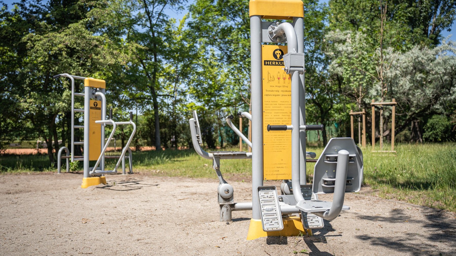 Galeria zdjęć przedstawia park Kasprowicza. Widać na nim roślinność, a także plac zabaw, siłownię zewnętrzną i halę Arena.