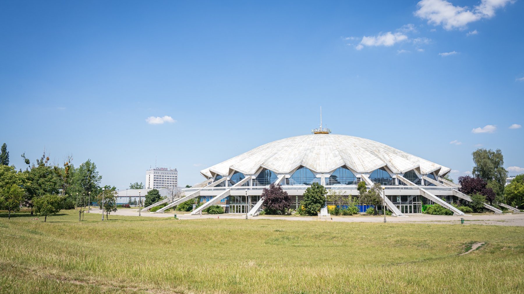 Galeria zdjęć przedstawia park Kasprowicza. Widać na nim roślinność, a także plac zabaw, siłownię zewnętrzną i halę Arena.