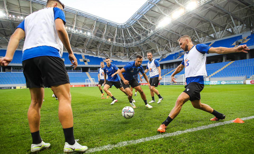 Grupa piłkarzy podaje piłkę miedzysobą. W tle stadion. - grafika artykułu