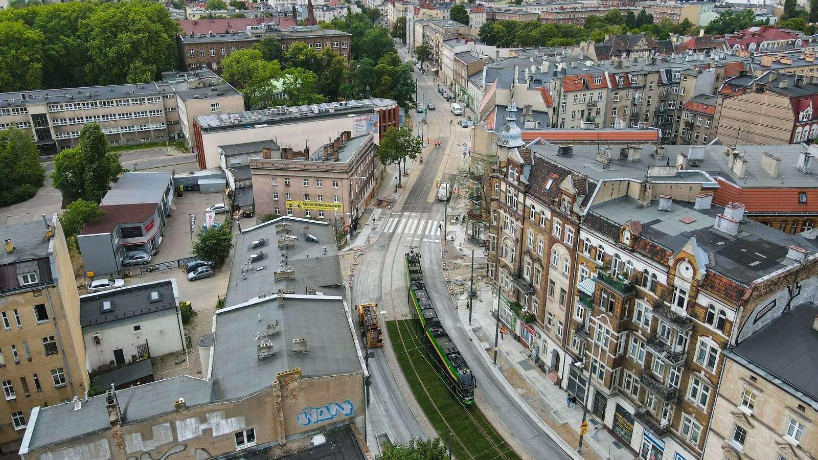 Na zdjęciu torowisko z lotu ptaka, w centrum widać tramwaj, w tle widać panoramę Poznania