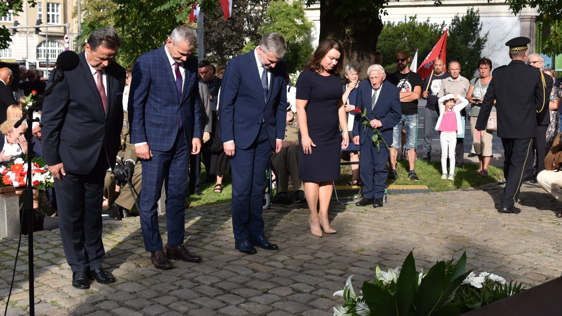 Na zdjęciu przedstawiciele władz rządu i samorządu składają wiązankę kwiatów, pochyleni