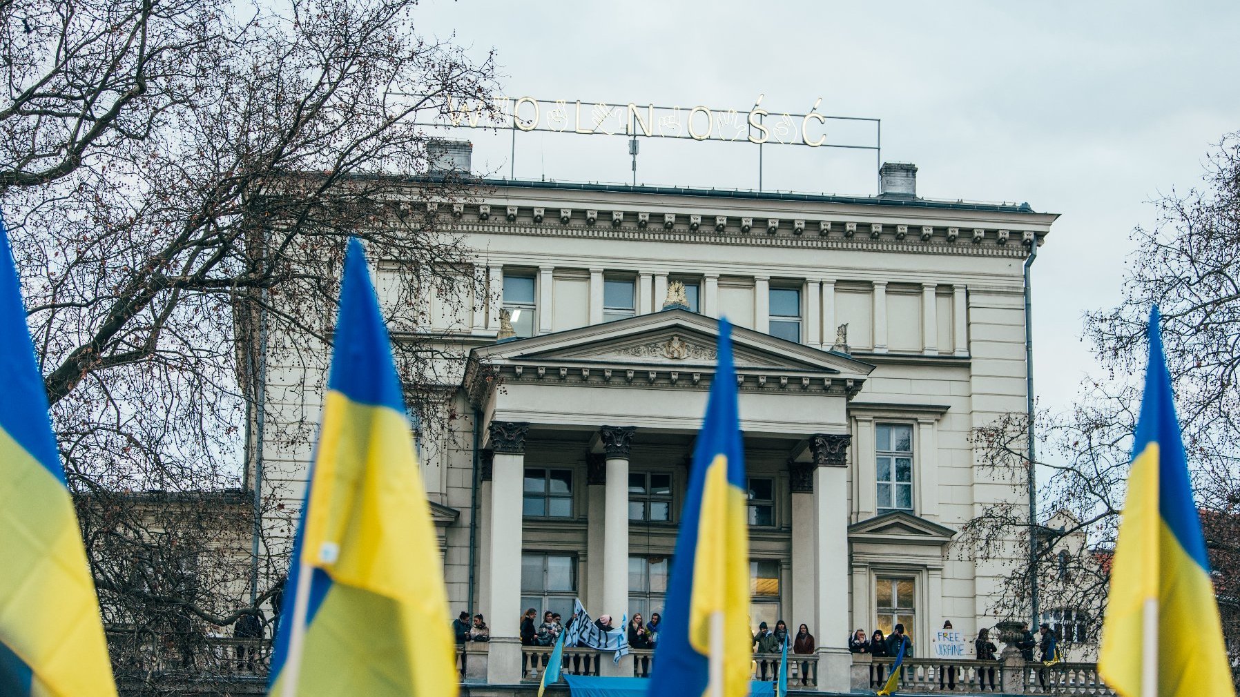 Flagi Ukrainy. W tle budynek Arkadii na placu Wolności z neonem "Wolność"