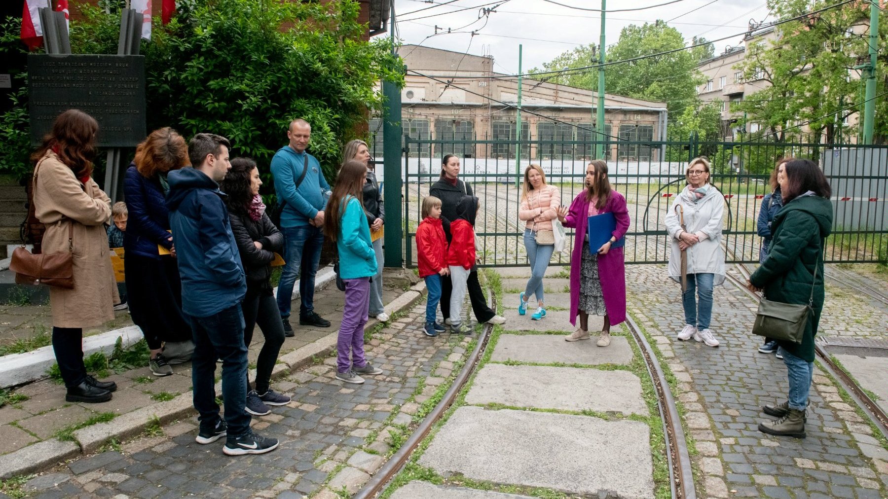 Grupa osób stoi przed zajezdnią tramwajową przy ul. Gajowej.