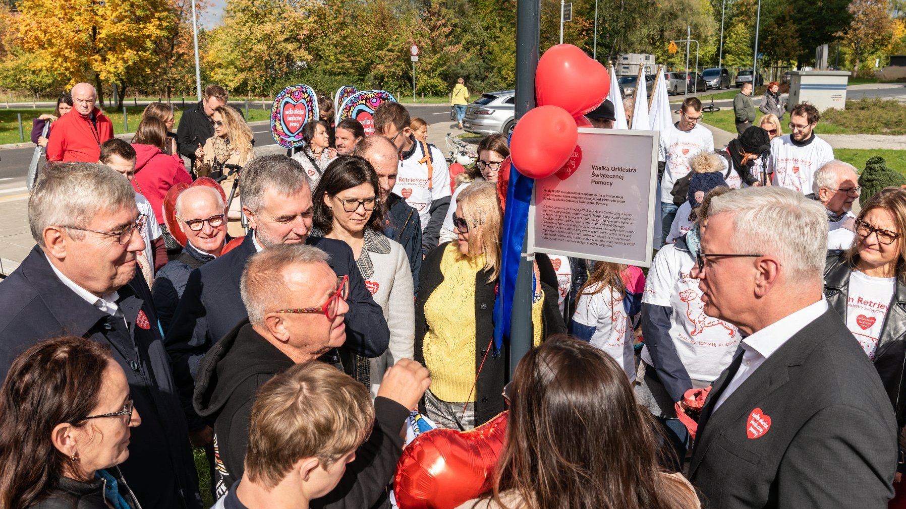 Na zdjęciu poznaniacy pod tablicą z nazwą skweru, w centrum Jurek Owsiak, obok samorządowcy i wolontariusze