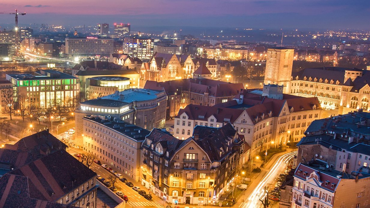 Na zdjęciu panorama Poznania po zmroku, w centrum zabudowa śródmiejska widziana z lotu ptaka