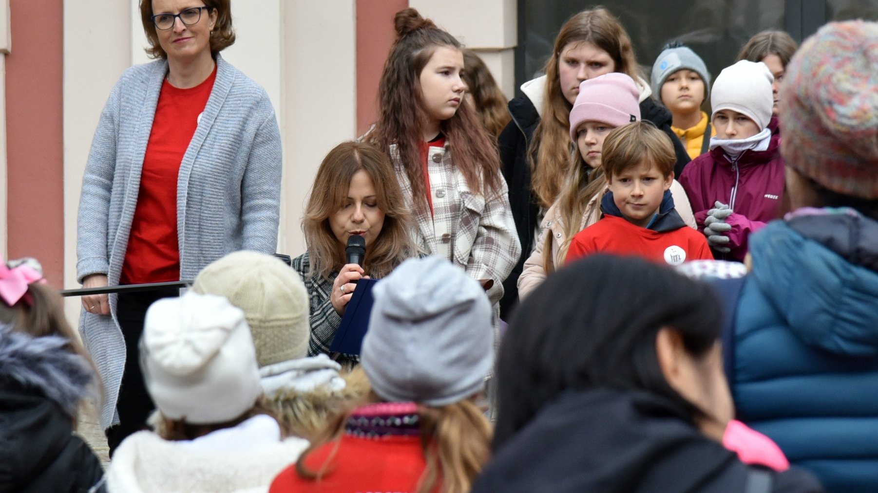 Na zdjęciu czytająca kobieta, otoczona dziećmi