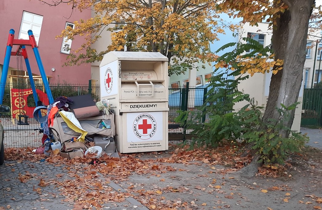 Na zdjęciu śmieci leżące przy kontenerze PCK na używaną odzież - grafika artykułu