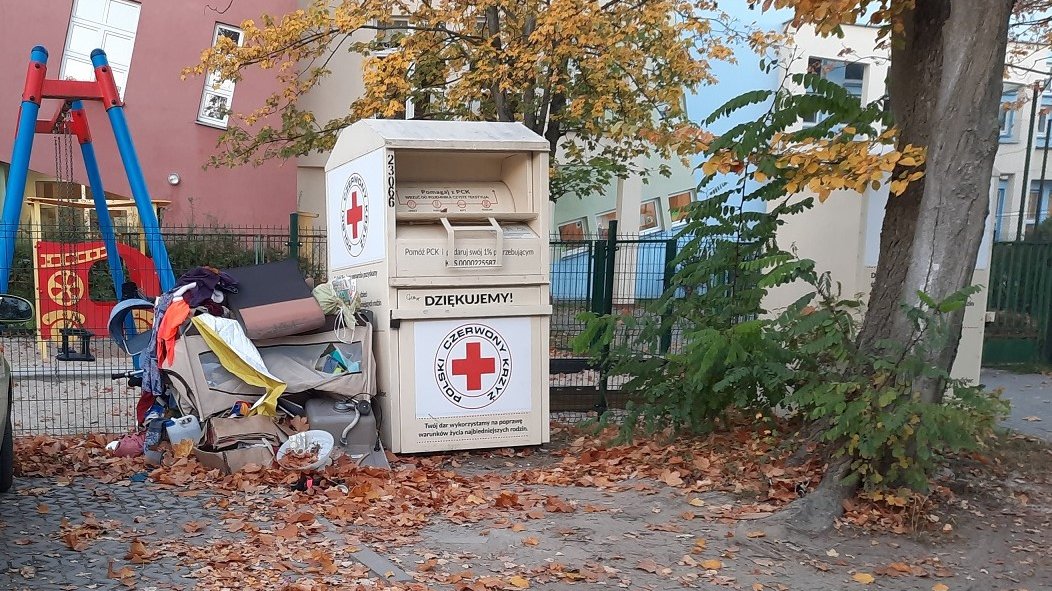 Na zdjęciu śmieci leżące przy kontenerze PCK na używaną odzież