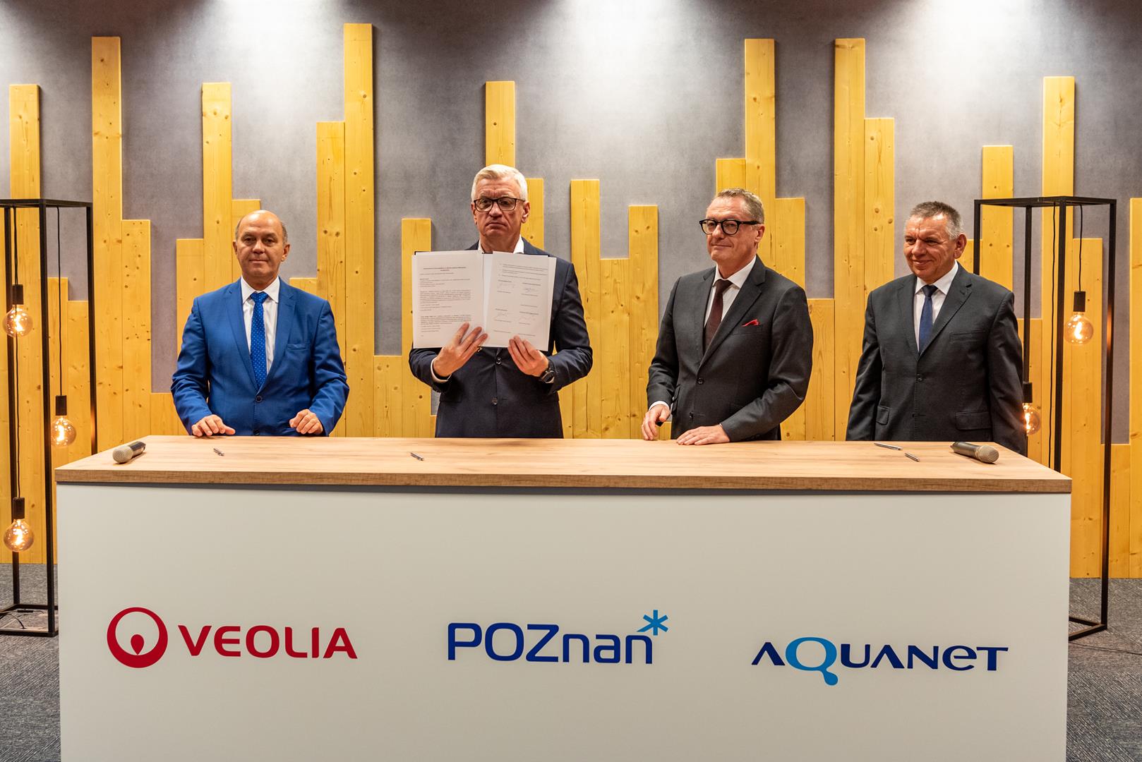 Czterej mężczyźni za stołem konferecyjnym, wśród nich prezydent Poznania, trzyma w dłoniach porozumienie - grafika artykułu