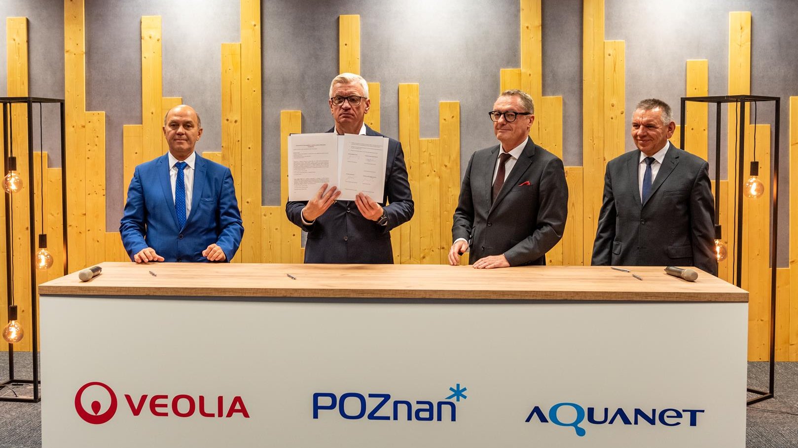 Czterej mężczyźni za stołem konferecyjnym, wśród nich prezydent Poznania, trzyma w dłoniach porozumienie