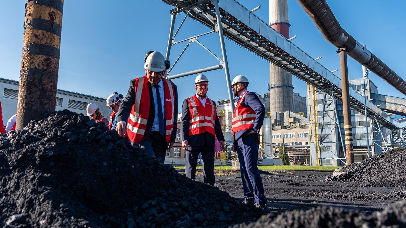 Na zdjęciu grupa osób - w tym prezydent Poznania - stojąca nad hałdą węgla