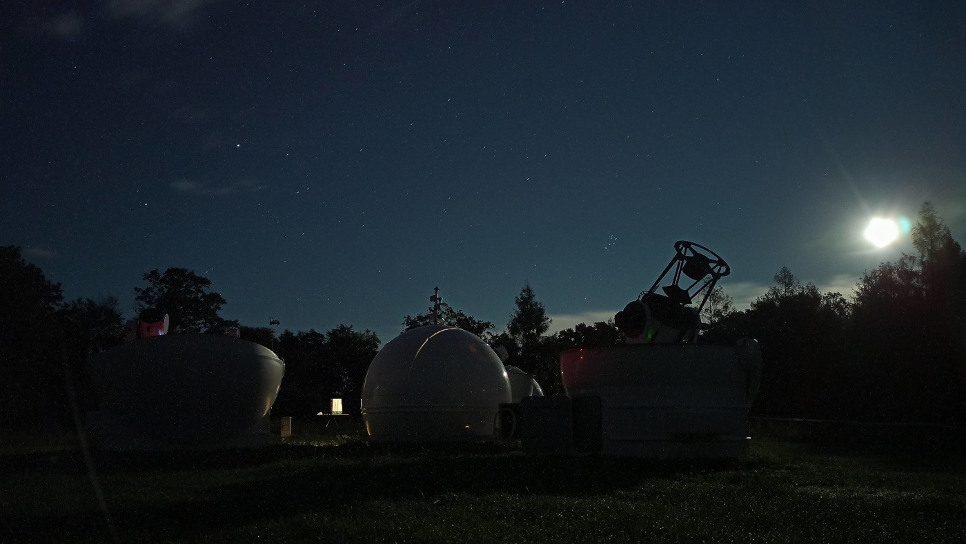 Budynki Obserwatorium Astronomicznego UAM, w tle nocne, rozgwieżdżone niebo. - grafika artykułu