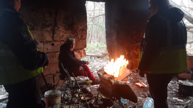 Na zdjęciu miejsce przebywania osób w kryzysie bezdomnościi, jedna osoba siedzi na krześle, obok niej ognisko