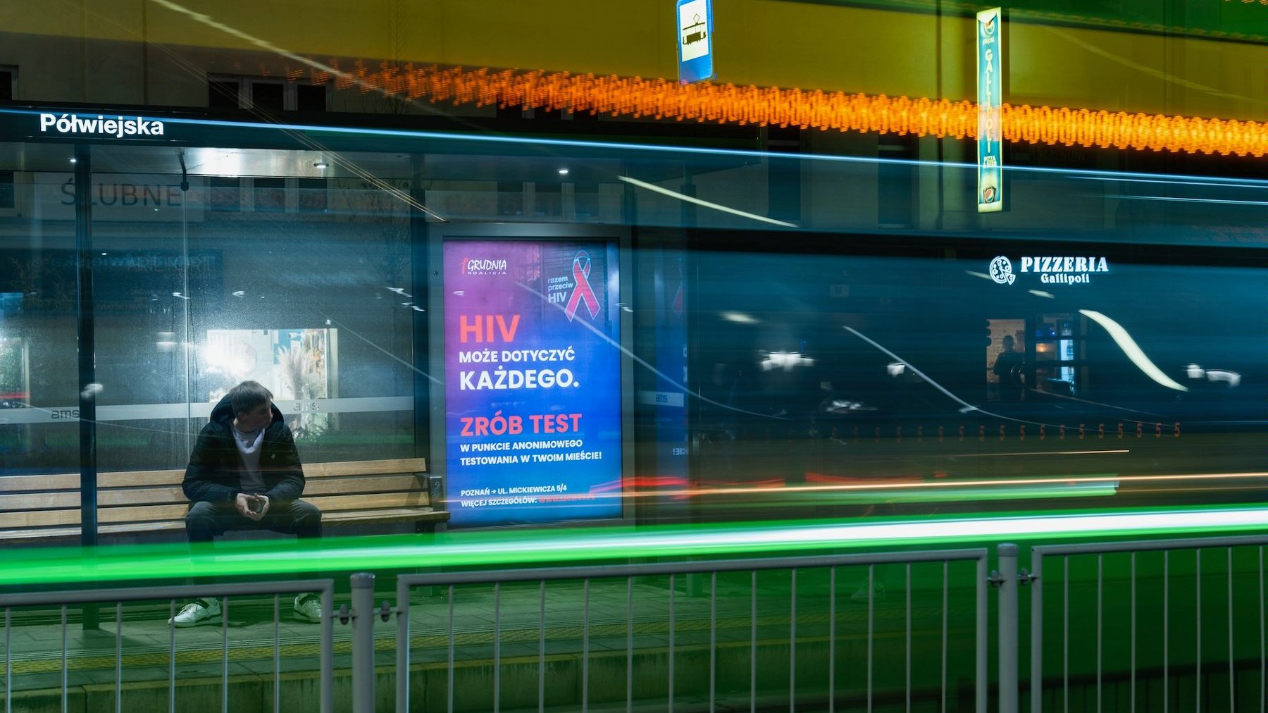 Na zdjęciu przystanek tramwajowy, na wiacie plakat informujący o testach na HIV