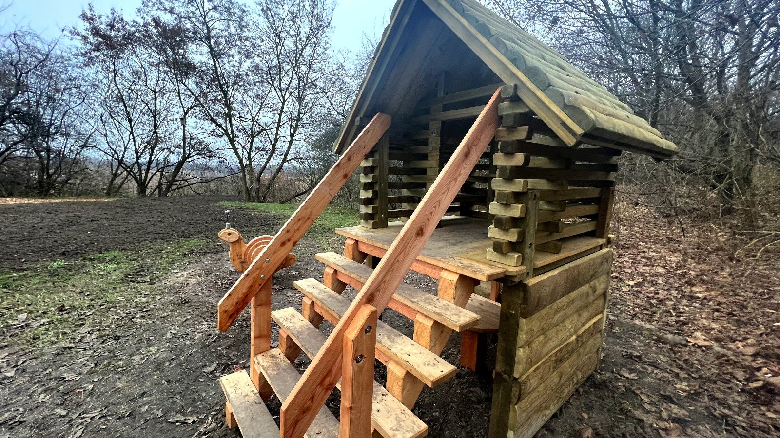 Galeria zdjęć przedstawia drewniane konstrukcje dla dzieci ustawione pośród zieleni