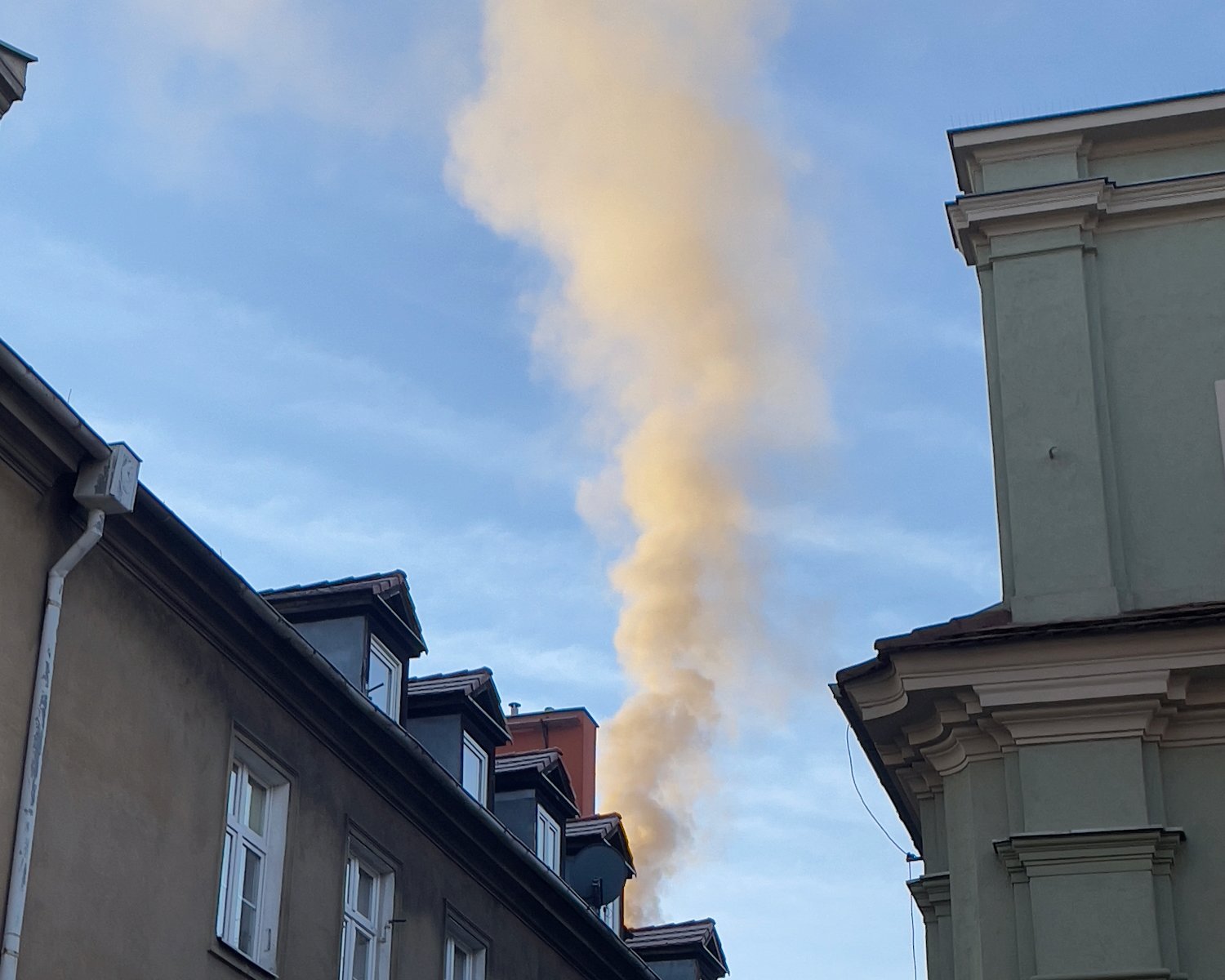 Zdjęcie poglądowe, dach domu z kominem, z którego unosi sie dym - grafika artykułu