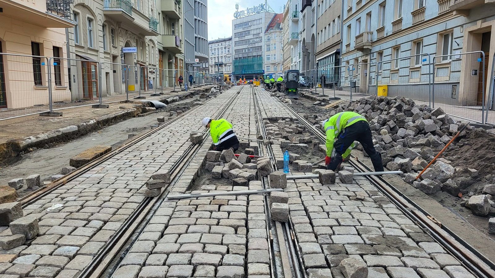 Na zdjęciu plac budowy, robotnicy układający kostkę brukową