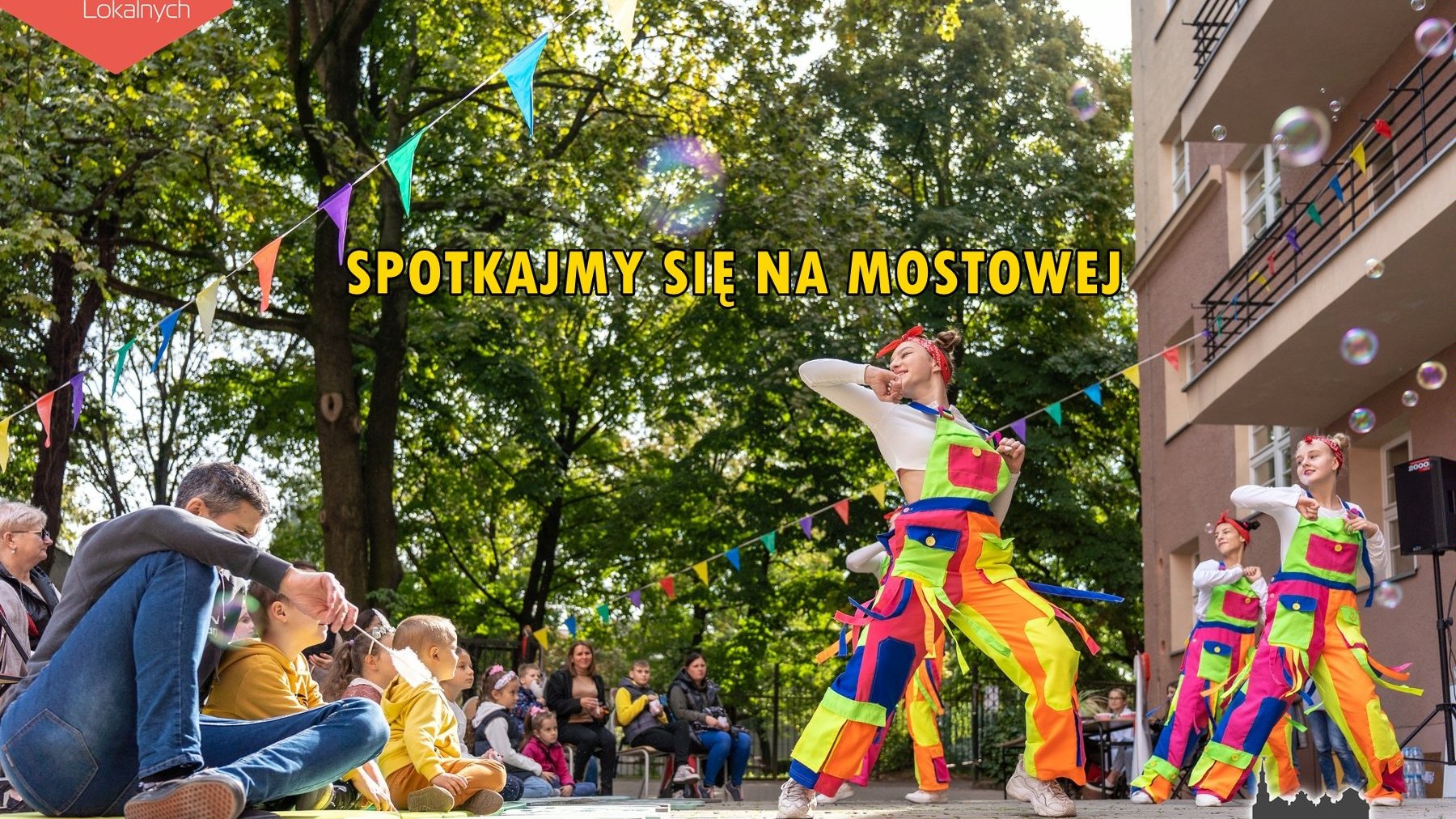 Zdjęcie grupy artystów na ulicy mostowej, napis: spotkajmy się na Mostowej