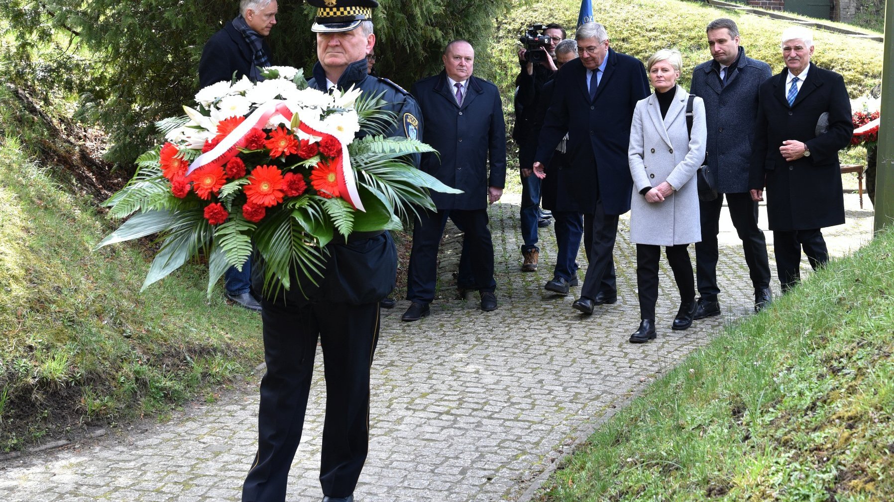 Na zdjęciu grupa osób składających wieniec z kwiatów