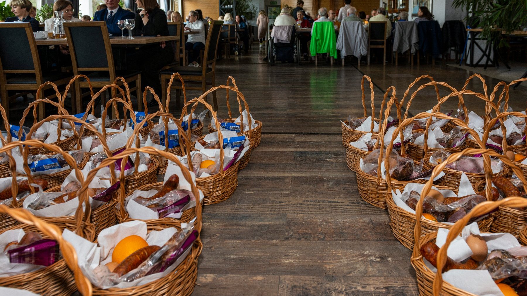 Na zdjęciu sala restauracji, na pierwszym planie kosze, w tle seniorzy