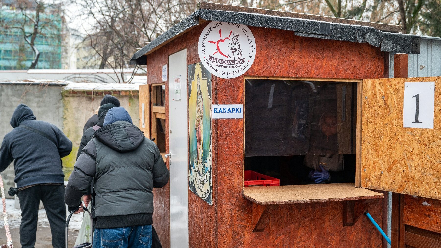 Na zdjęciu budka stojąca na podwórku jadłodajni, obok przechodzą ludzie