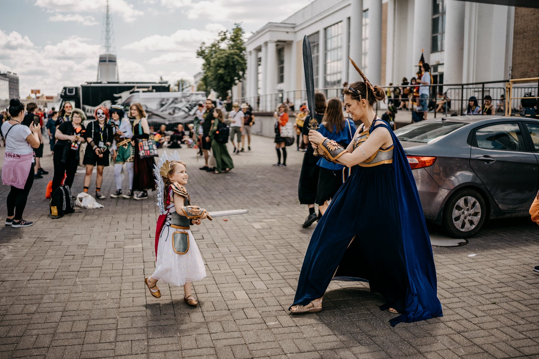 Na pierwszym planie przebrana mama z córką. W tle inni cosplajowcy na terenie MTP - grafika artykułu