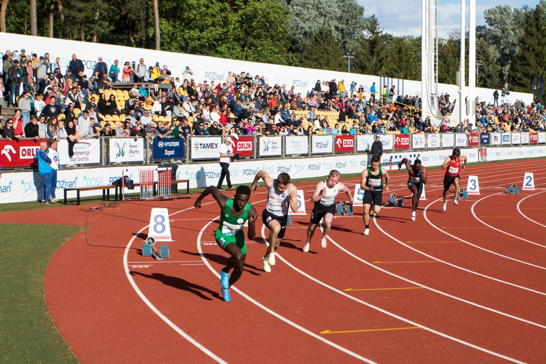 Start zawodników w biegu na 200 metrów. W tle publiczność na trybunach stadionu na Golęcinie - grafika artykułu