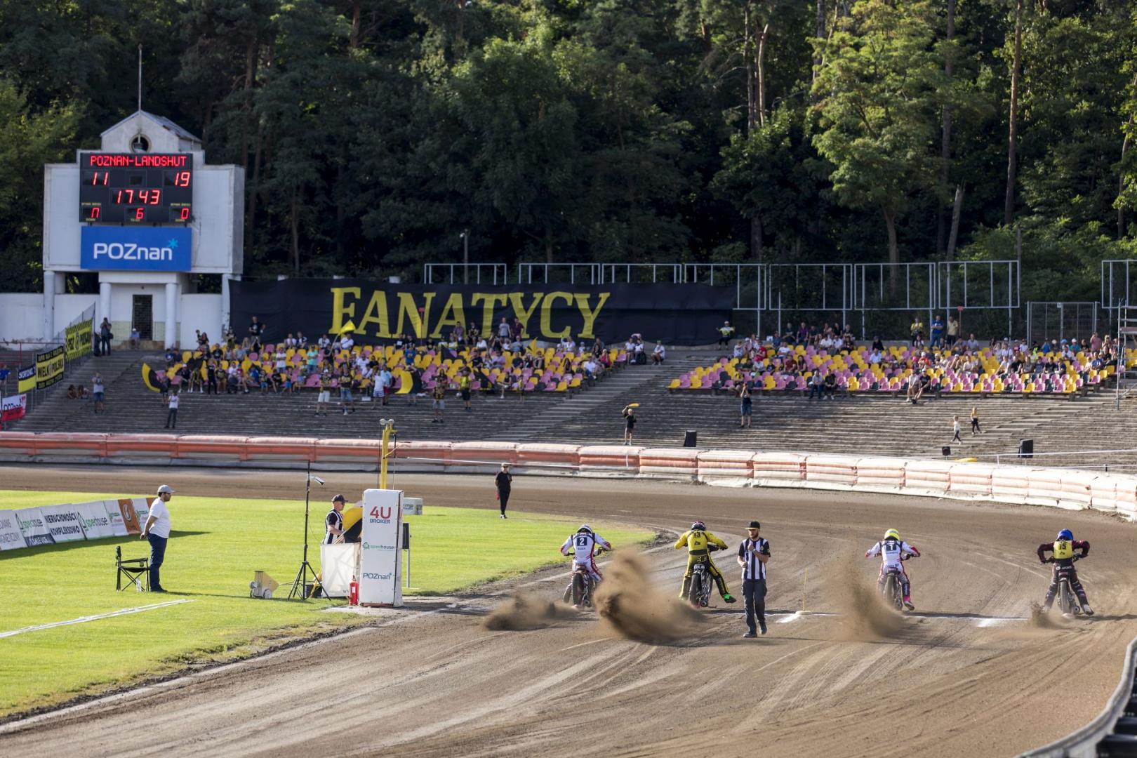 Na zdjęciu widać stadion żużlowy na Golęcinie, startujących żużlowców i kibiców na trybunach - grafika artykułu