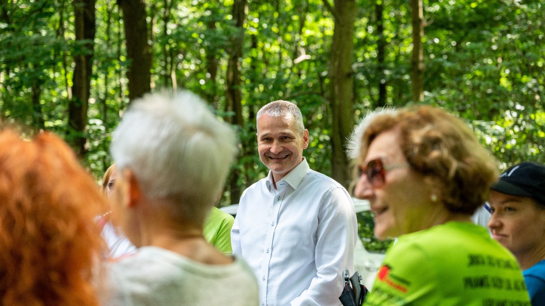 Galeria zdjęć przedstawia grupę seniorów w strojach sportowych z kijkami do nordic walking.