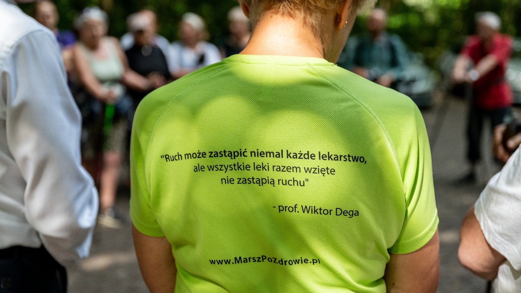 Galeria zdjęć przedstawia grupę seniorów w strojach sportowych z kijkami do nordic walking.