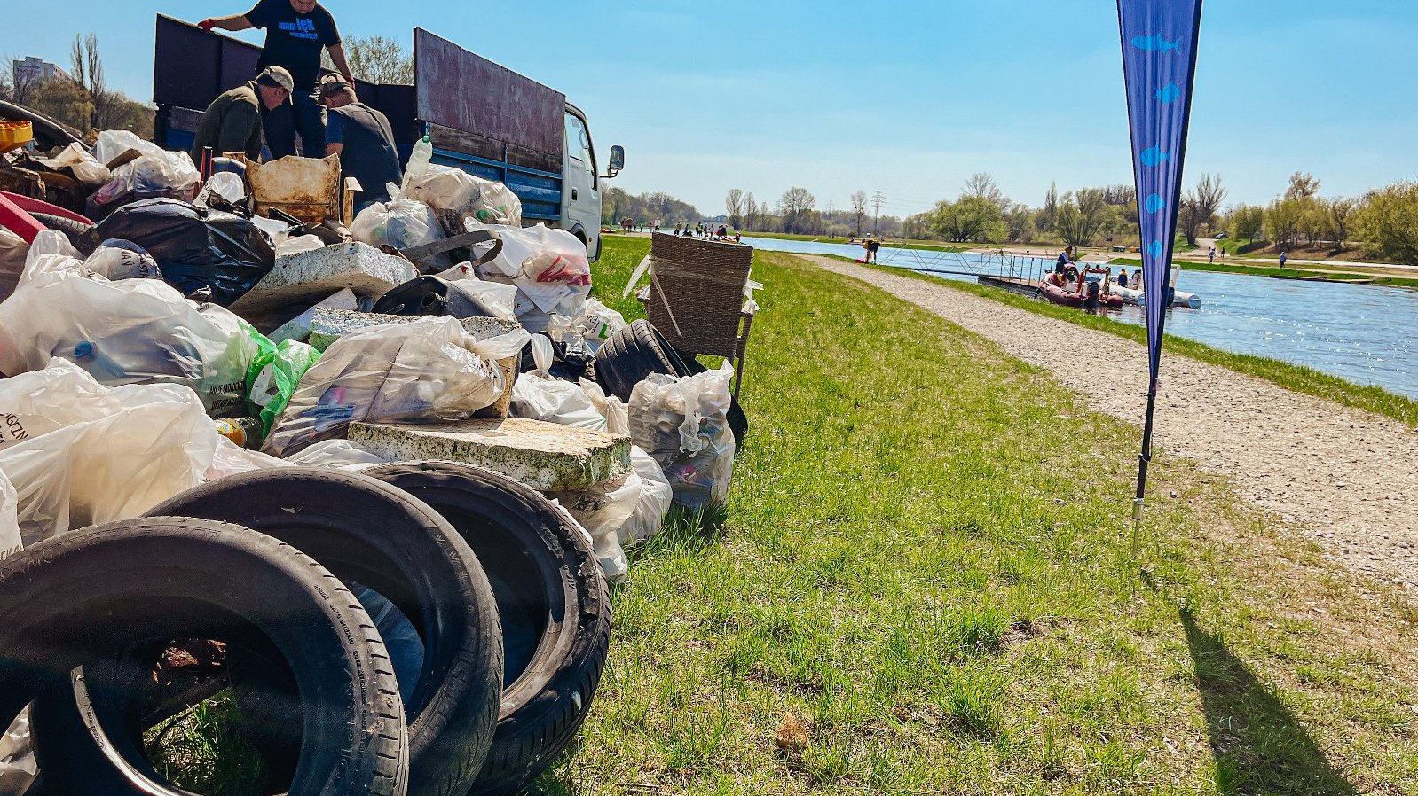 Na zdjęciu zebrane śmieci w workach leżące obok rzeki