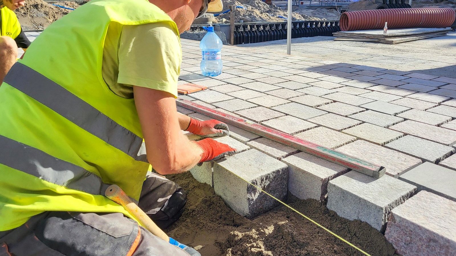 na zdjęciu robotnicy układający kostkę na rynku, zbliżenie