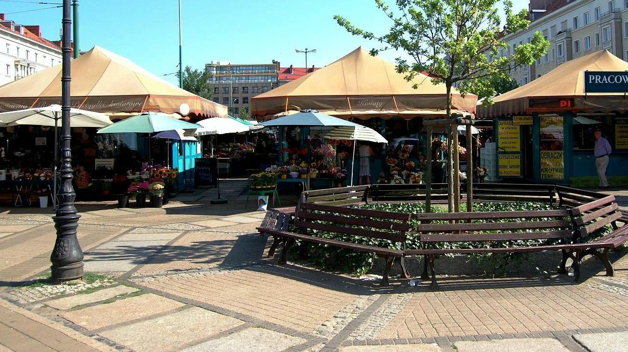 Na zdjęciu plac Wielkopolski ze straganami oraz ławkami ustawiony w koło dookoła drzewa