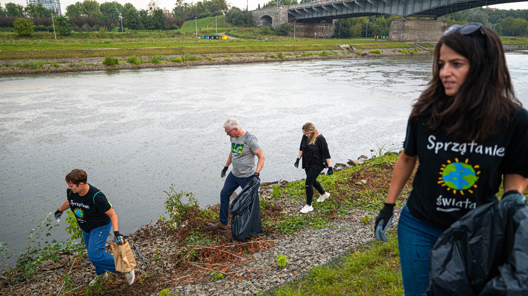 Na zdjęciu cztery osoby sprzątają brzeg rzeki, wśród nich prezydent Poznania