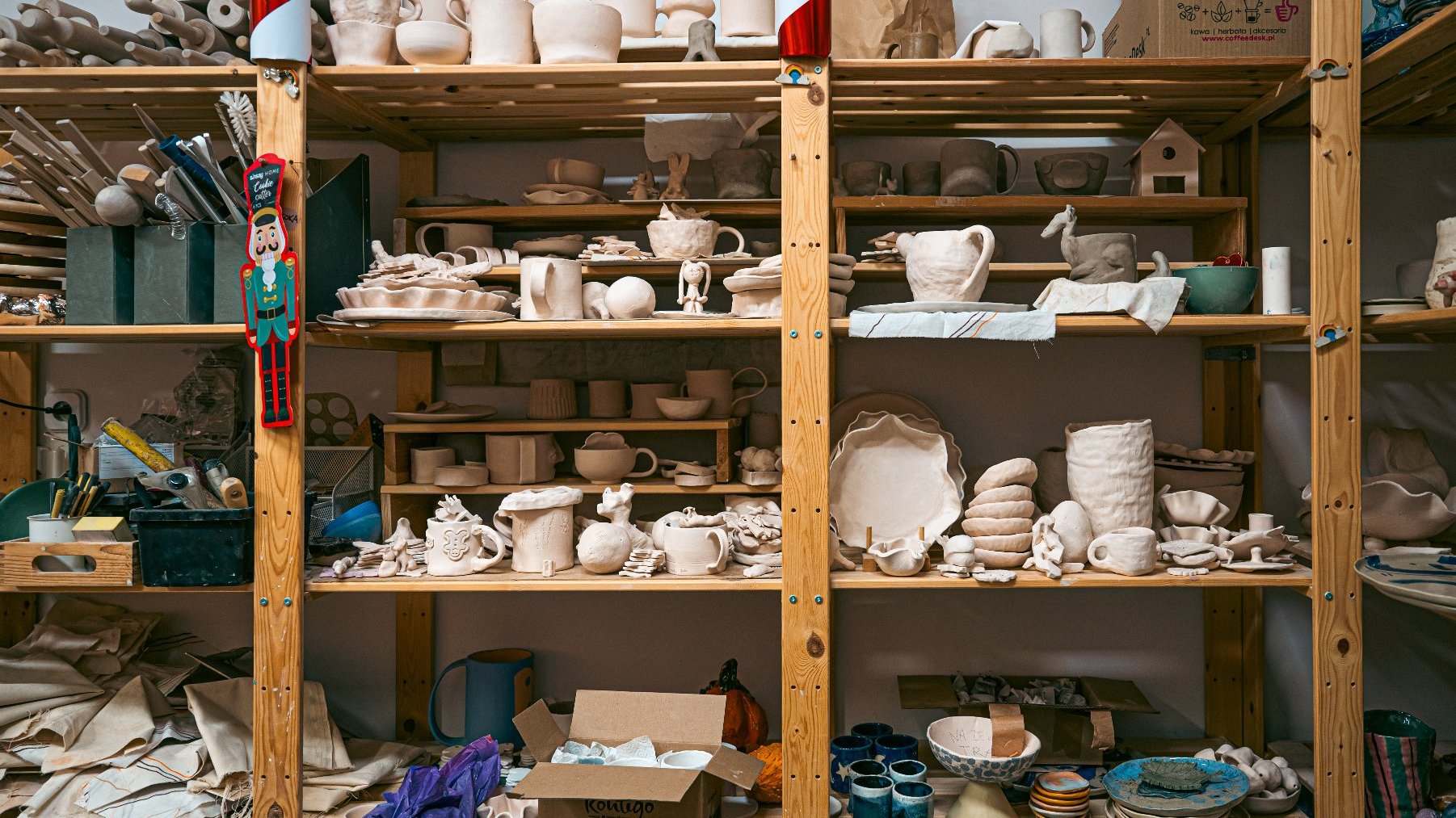 Zdjęcie przedstawia półki, na których widać mnóstwo przedmiotów z gliny - figurek, talerzy, kubków, wazonów.