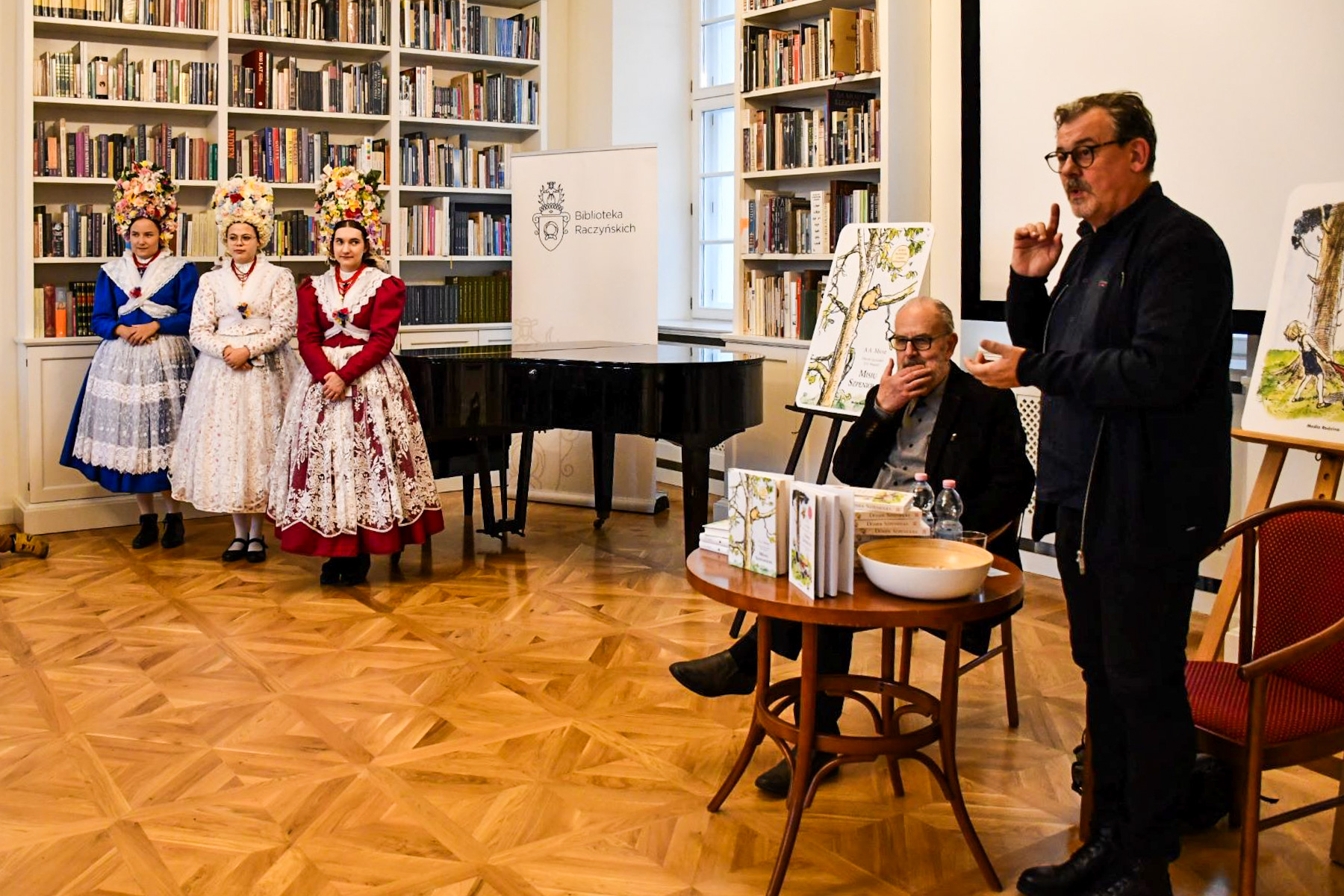 Na zdjęciu spotkanie autorskie z tłumaczem, obok trzy kobiety w strojach bamberskich - grafika artykułu