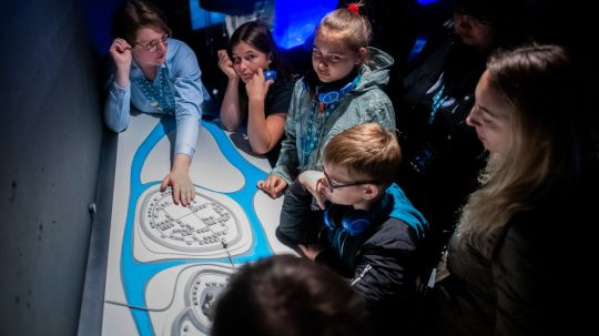 Zdjęcie przedstawia dzieci przed mapą Ostrowa Tumskiego.
