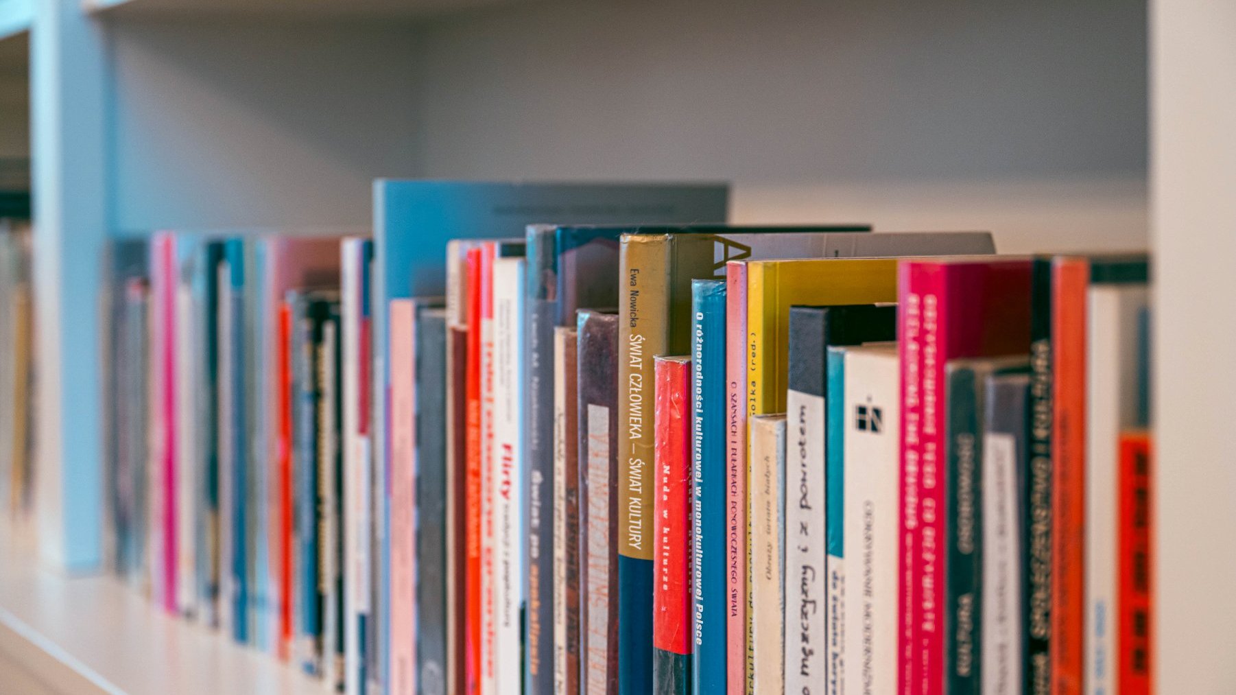 Galeria zdjęć przedstawia wnętrza głównego gmachu Biblioteki Raczyńskich. Na białych, zdobionych pólkach stoją rzędy książek.