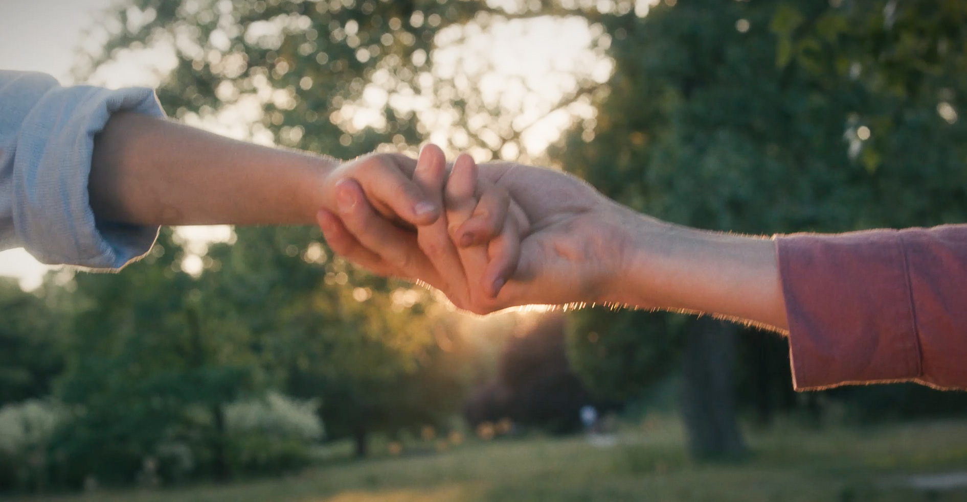 Na zdjęciu kadr z filmu promującego pieczę zastępczą, widać dwie osoby trzymające się za ręce - grafika artykułu